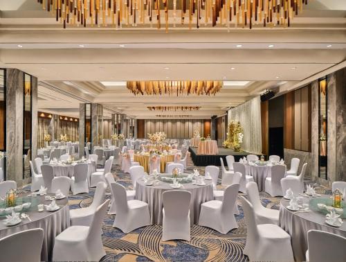 a ballroom with white tables and chairs and a chandelier at voco Orchard Singapore by IHG in Singapore