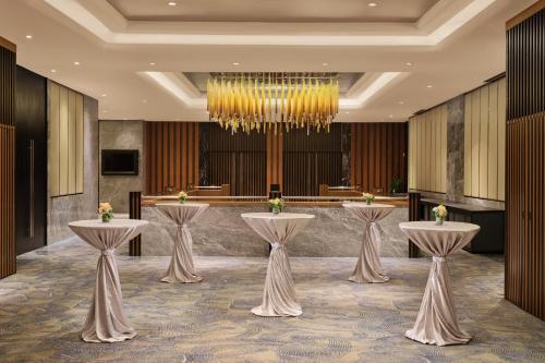 a lobby with three tables and a chandelier at voco Orchard Singapore by IHG in Singapore