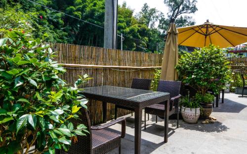 a table and chairs with an umbrella and a fence at Zhangjiajie Forest Park Youth Hostel in Zhangjiajie