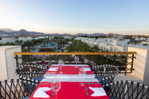 a red table with wine glasses on top of a balcony at Swissôtel Sharm El Sheikh - Ultra All Inclusive Collection in Sharm El Sheikh