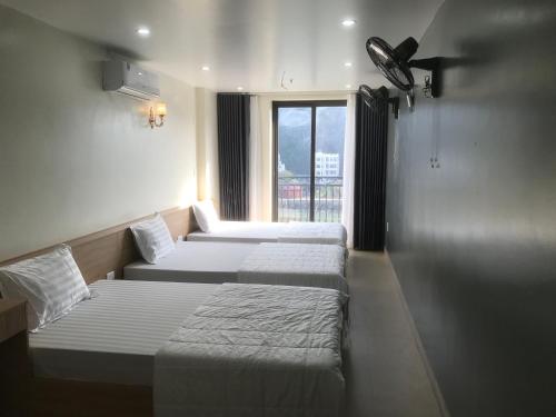 three beds in a room with a window at Sea Balcony Hotel in Cat Ba