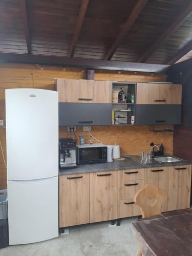 a kitchen with a white refrigerator and wooden cabinets at La Grasu' Sauna&ciubar in Dodeni