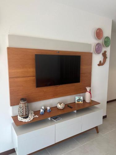 a living room with a television on a wall at Apartamento em condomínio com passeio incluso in Baixio