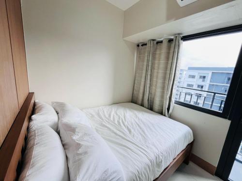 a small bed in a room with a window at Modern City Escape Near MOA and Airport with Balcony and Fast WiFi in Manila