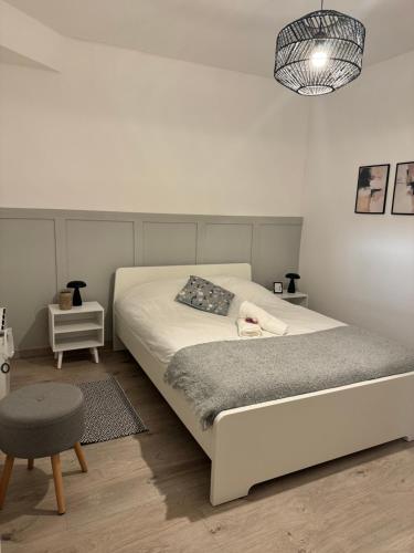 - une chambre blanche avec un lit et un tabouret dans l'établissement Maison au Cœur de Béziers, à Béziers