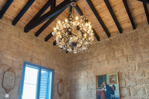 a chandelier in a room with a stone wall at Le Voyageur By the Sea - Furnished Rooms in Larnaka