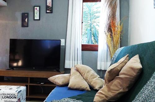 a living room with a couch with pillows and a television at Temporada Belas Casas in São Pedro