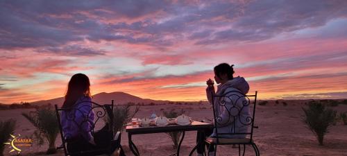 a man and woman sitting at a table in the desert at Asafar Luxury Camp in Merdani