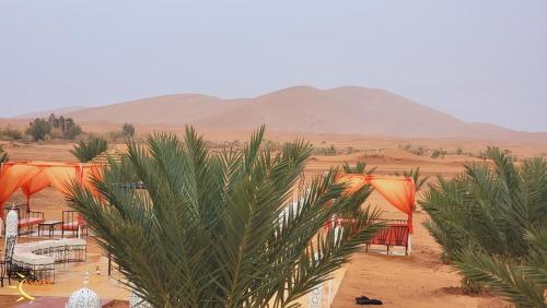 a view of a desert with tents and palm trees at Asafar Luxury Camp in Merdani