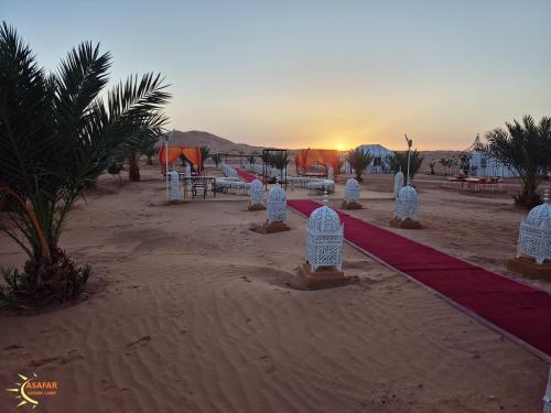 a beach with a red carpet and tables and a sunset at Asafar Luxury Camp in Merdani