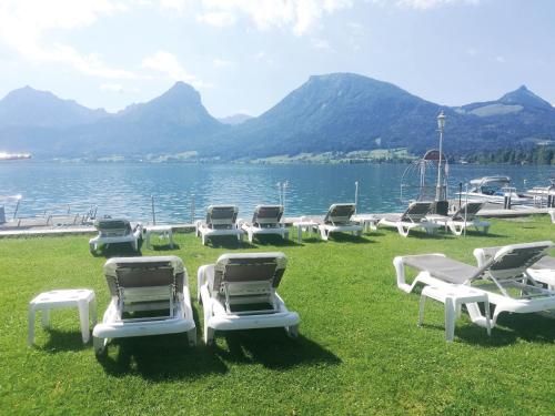 a group of lounge chairs sitting on the grass by the water at Romantik Residenz (Ferienwohnungen Hotel Im Weissen Rössl) - Dependance in St. Wolfgang