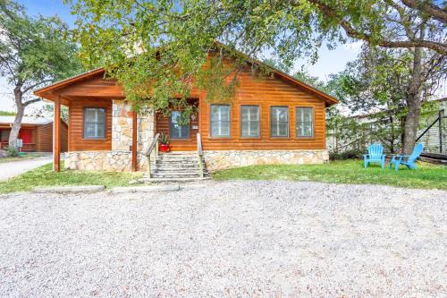 a log cabin with two blue chairs in front of it at Wimberley Log Cabins Resort and Suites- The Oak Lodge in Wimberley