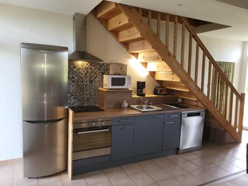 une cuisine avec un réfrigérateur en acier inoxydable et un escalier. dans l'établissement Gîte au cœur du château Flotis, à Castelnau-dʼEstrétefonds