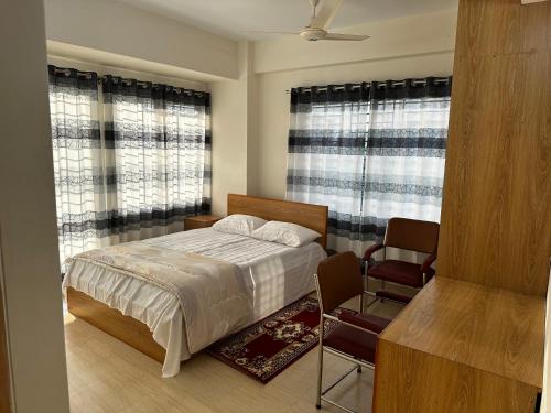a bedroom with a bed and a chair and windows at Creative Palace in Nārāyanganj