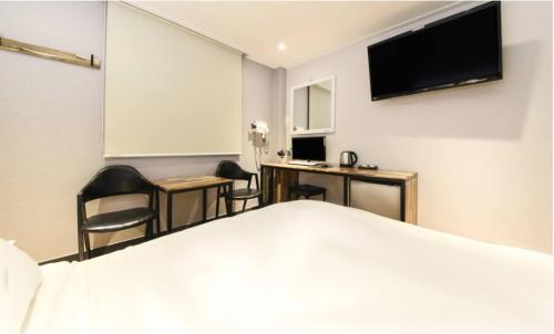 a hotel room with a bed and a desk and a tv at illuwa M in Seoul
