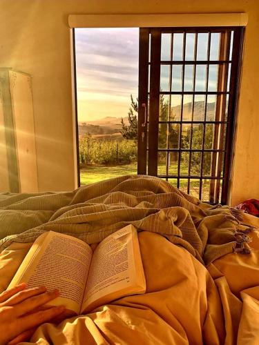 an open book laying on a bed with a window at Babylons Tower Cottage in Caledon
