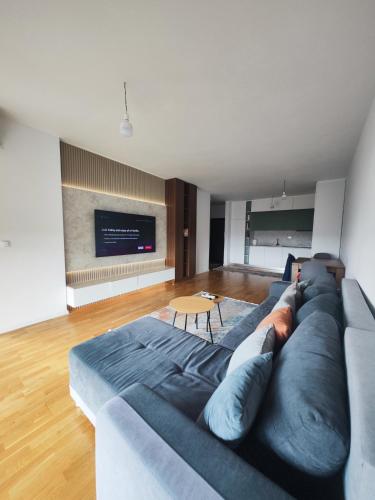a living room with a blue couch and a television at Skyline Apartment 1 in Peje