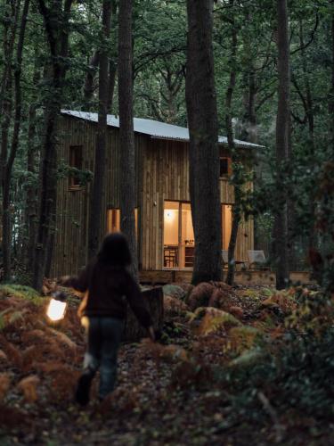 a woman walking in front of a cabin in the woods at Youza ecolodge in La Couture-Boussey