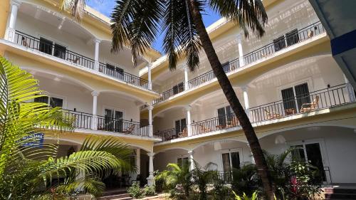 a large white building with a palm tree in front of it at Morjim Sunset Guesthouse - 300 meter to Morjim Beach in Morjim