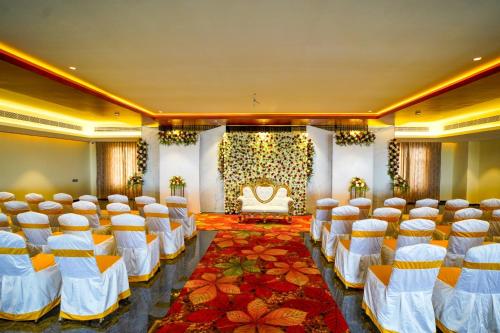 a banquet hall with white chairs and a stage at Hotel Yathin in Mysore