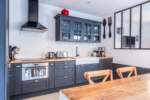 une cuisine avec des placards gris et une table en bois dans l'établissement Maison d'architecte centre Tours jardin, climatisation, parking 5 p, à Tours