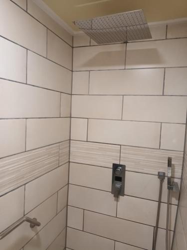 a white tiled shower with a soap dispenser at Gite Happy Sun Flower in Virlet