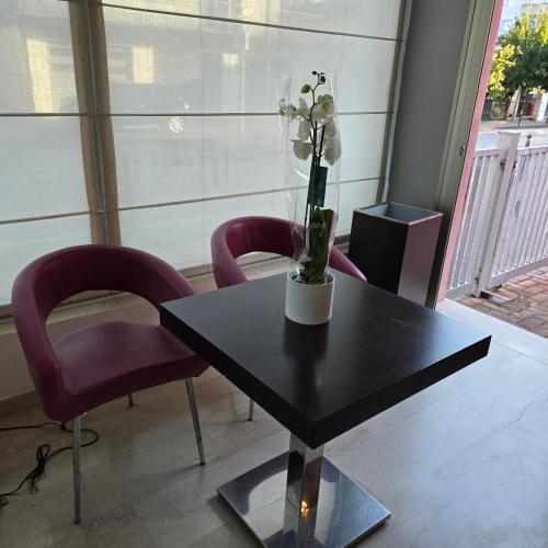 a table with purple chairs and a vase with flowers on it at Hotel Marco Polo Airport hotel in Campalto