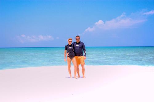 a man and woman standing on a white beach at Sabba Beach Suite , Fodhdhoo - Maldives in Velidhoo