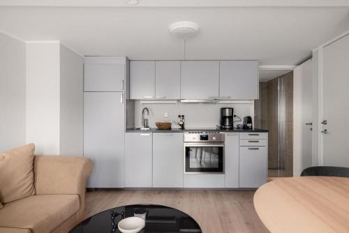 eine Küche mit weißen Schränken, einem Sofa und einem Tisch in der Unterkunft Nordnes Apartment in Bergen