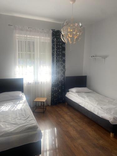 a bedroom with two beds and a chandelier at Dworek Kolorado dom 180 m2 na wyłączność - wyposażony in Klimki