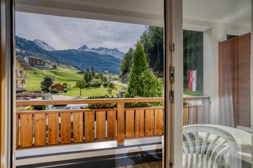 a room with a balcony with a view of mountains at Hotel Erika in Nauders