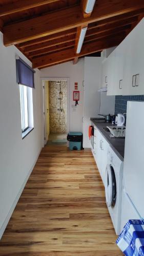 a kitchen with white counters and a wooden floor at Casa ao centro - Apartamento Angrego in Angra do Heroísmo