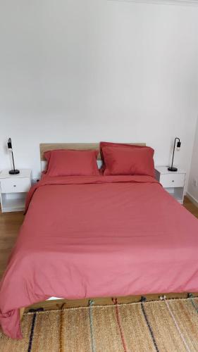 ein Bett mit roten Laken und roten Kissen in der Unterkunft Casa ao centro - Apartamento Angrego in Angra do Heroísmo