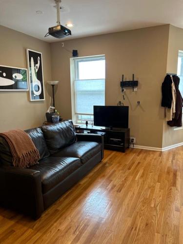 a living room with a leather couch and a flat screen tv at Gorgeous North Kenwood Hyde Park Unit in Chicago