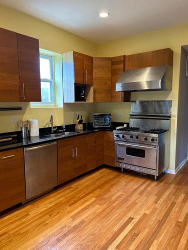 a kitchen with a stainless steel stove and wooden cabinets at Gorgeous North Kenwood Hyde Park Unit in Chicago