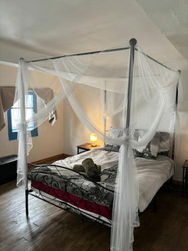 une chambre avec un lit à baldaquin avec des rideaux blancs dans l'établissement Central apartment in Quillan, à Quillan