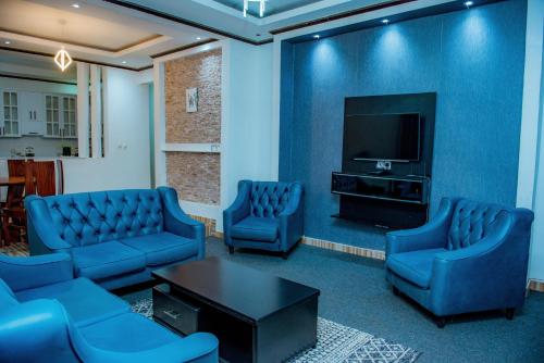 Una sala de espera con sillas azules y un televisor. en Prime Luxury Apartments, en Kigali
