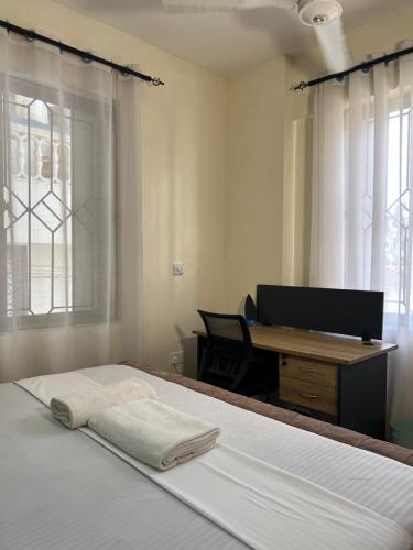 a bedroom with a bed with a desk and a computer at beautifully furnished one bedroom apartment in vok off nyali road in Mombasa