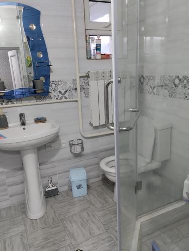 a bathroom with a sink and a toilet and a shower at White cute house in Karakol