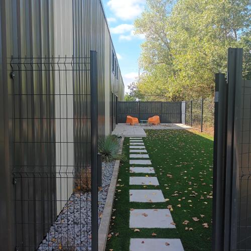 un jardin avec une clôture à côté d'un bâtiment dans l'établissement Loft du Bugey, à Loyettes