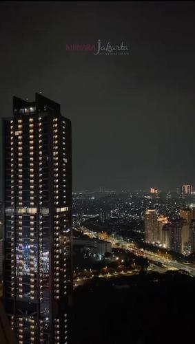 a city skyline at night with a tall building at Menara Jakarta Condo JI Expo PRJ by Blezz in Jakarta
