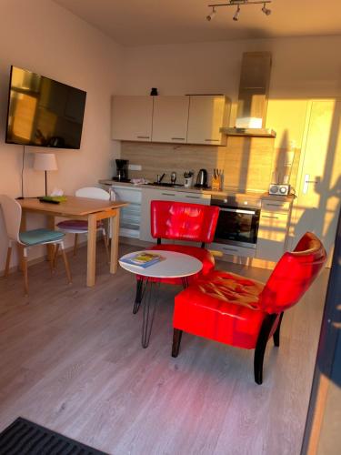 a kitchen with red chairs and a table and a kitchen with a counter at Ferienwohnung Ostseeblick am Breitling Whg 5 in Malchow