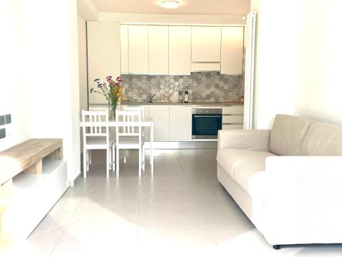 a white living room with a couch and a kitchen at Casa delle rondini in Rovereto