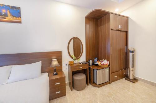 a bedroom with a bed and a vanity with a mirror at Huyền 179 in Da Lat