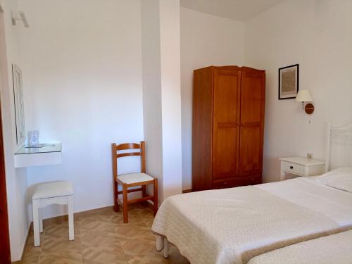 a bedroom with a bed and a wooden cabinet and a chair at Rena Studios in Paleokastritsa