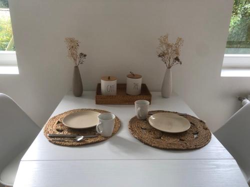 une table avec deux assiettes, deux tasses et un vase dans l'établissement La Bercerie, à Peuplingues