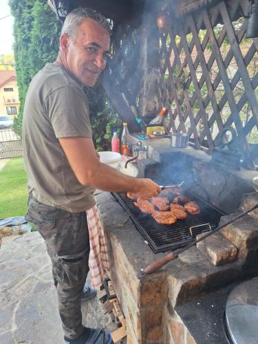 a man is cooking sausages on a grill at Pensiunea Flori in Vaţa de Jos
