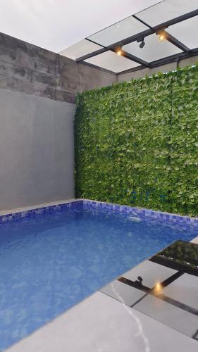 a swimming pool in a room with a green wall at Villa Pondok Kelapa Batu in Batu