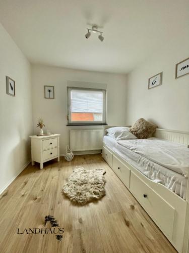 a white bedroom with a bed and a window at FeWo Büdingen - Landhaus in Büdingen