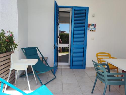a patio with chairs and tables and a blue door at Endless Summer in Fontane Bianche